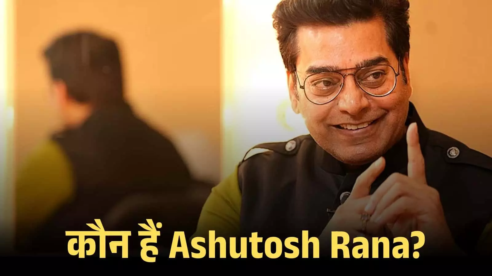 चश्मा पहने हुए अभिनेता आशुतोष राणा एक इंटरव्यू के दौरान हाथ से इशारा करते हुए दिख रहे हैं।