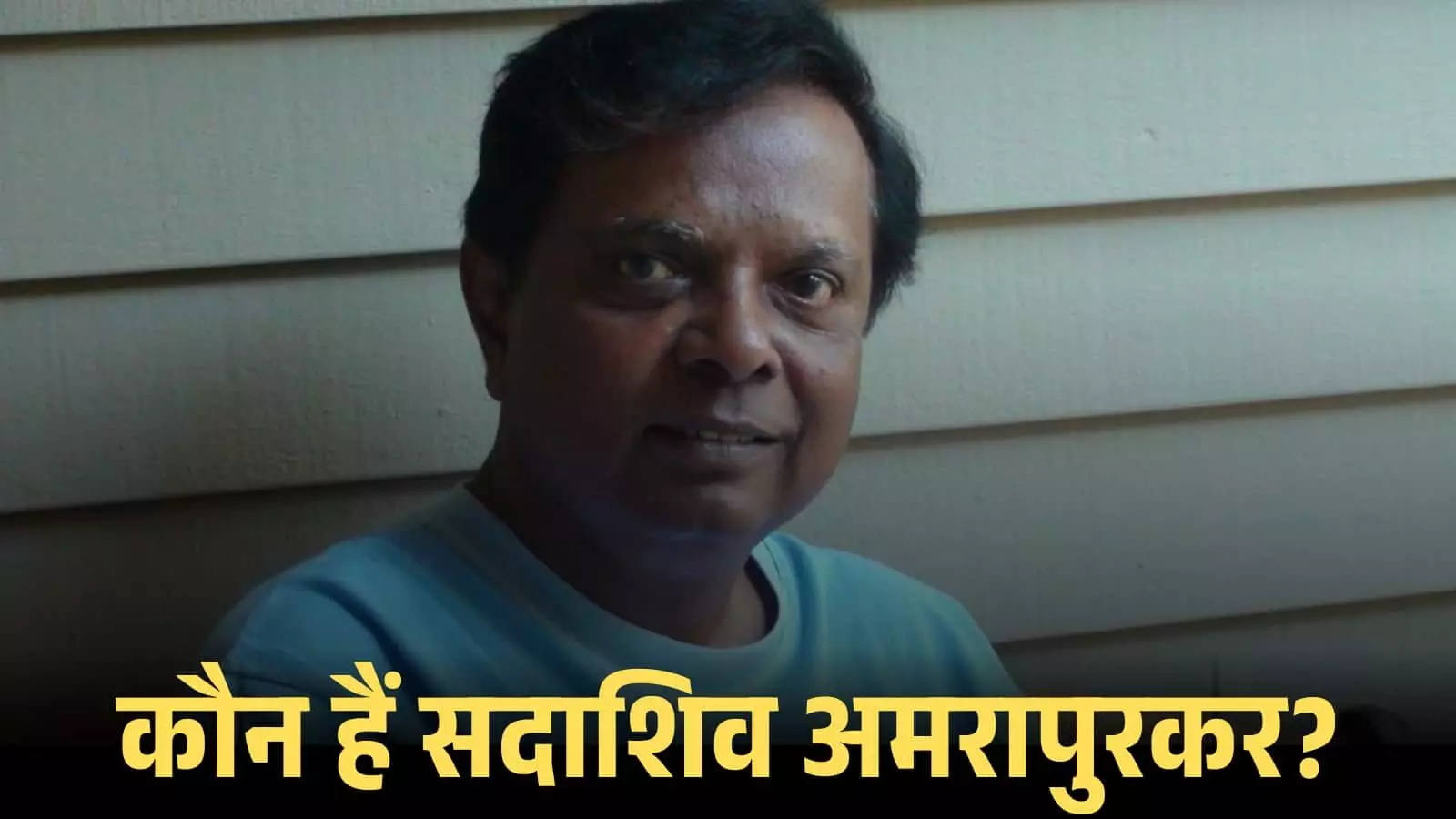 नीले रंग की टी-शर्ट पहने हुए सदाशिव अमरापुरकर एक सादे बैकग्राउंड के सामने कैमरे की ओर देख रहे हैं। नीले रंग की टी-शर्ट पहने हुए सदाशिव अमरापुरकर एक सादे बैकग्राउंड के सामने कैमरे की ओर देख रहे हैं।