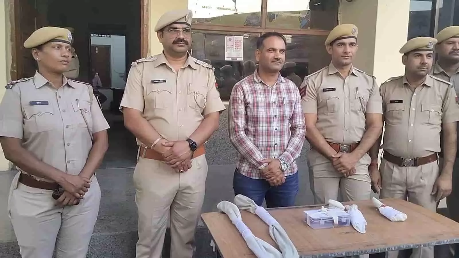 नाथद्वारा थाने के बाहर खड़े पुलिस अधिकारी मेज पर रखे बरामद हथियारों के साथ दिखाई दे रहे हैं।