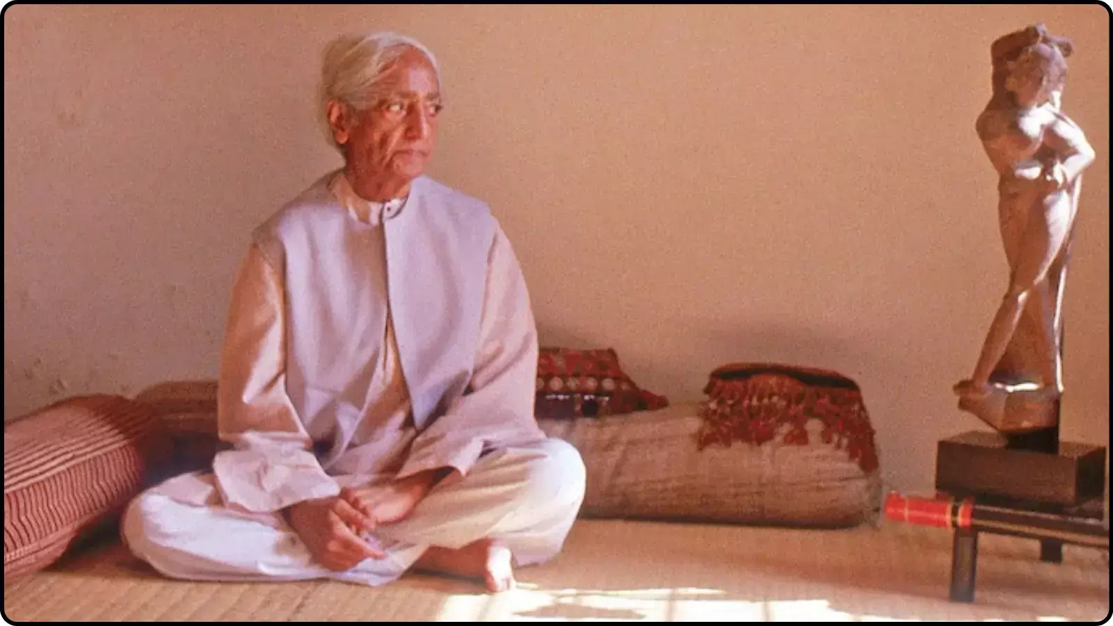 जमीन पर बैठकर चिंतन करते सफेद बालों वाले जिद्दू कृष्णमूर्ति और उनके पास रखी एक मूर्ति।