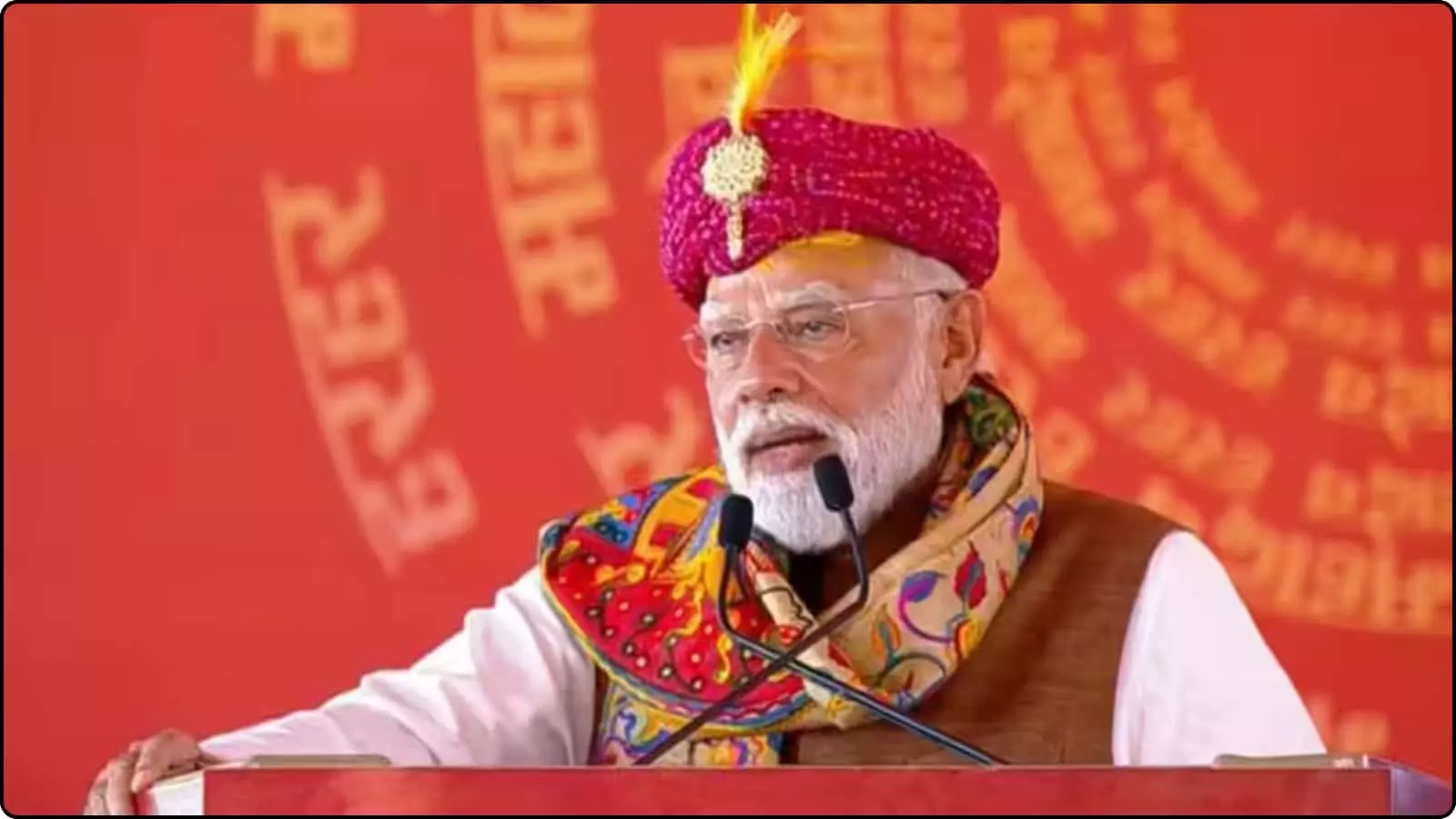 हर हर महादेव लिखे मंच से भाषण देते लाल पगड़ी पहने प्रधानमंत्री नरेंद्र मोदी। हर हर महादेव लिखे मंच से भाषण देते लाल पगड़ी पहने प्रधानमंत्री नरेंद्र मोदी।