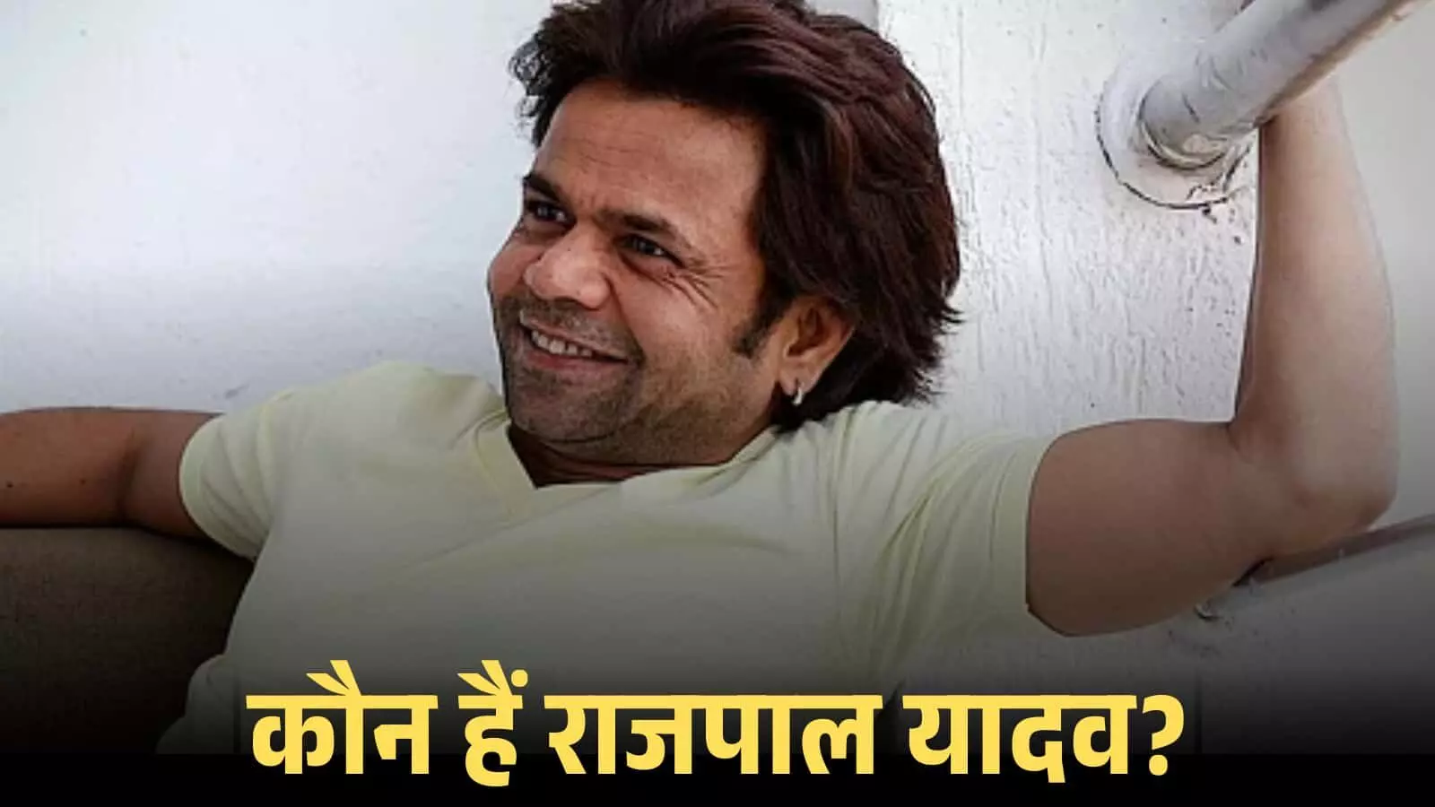 सफेद टी-शर्ट पहने मुस्कुराते हुए अभिनेता राजपाल यादव सोफे पर बैठे हुए। सफेद टी-शर्ट पहने मुस्कुराते हुए अभिनेता राजपाल यादव सोफे पर बैठे हुए।