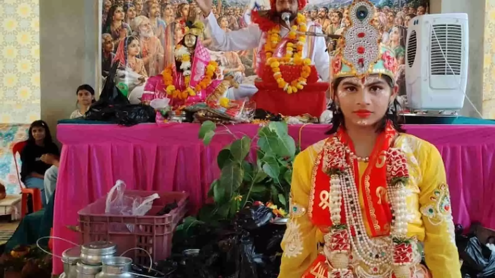 भुसावर में श्रीमद् भागवत कथा के दौरान भगवान कृष्ण के स्वरूप में सजा बालक और पृष्ठभूमि में धार्मिक चित्र।