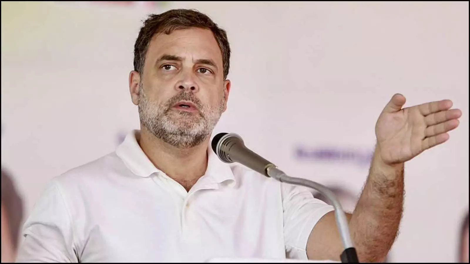 सफेद टी-शर्ट पहने माइक के सामने हाथ से इशारा करते हुए भाषण देते राहुल गांधी। सफेद टी-शर्ट पहने माइक के सामने हाथ से इशारा करते हुए भाषण देते राहुल गांधी।