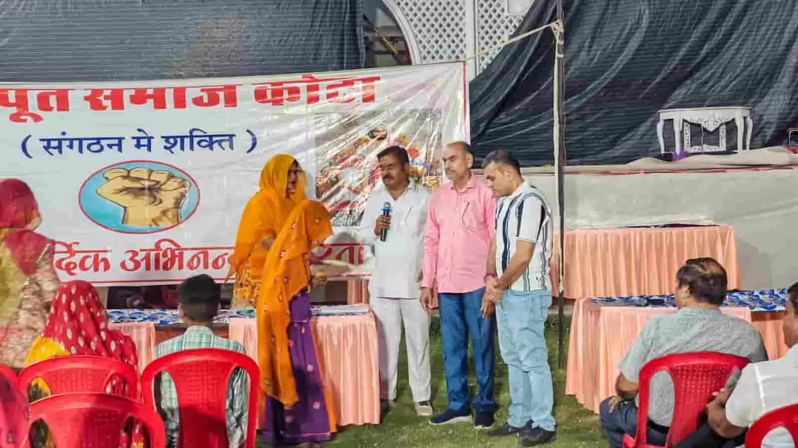 कोटा के कंसुआ में आयोजित सामाजिक कार्यक्रम के दौरान मंच पर उपस्थित अतिथि और आर्थिक सहायता प्राप्त करती महिला।