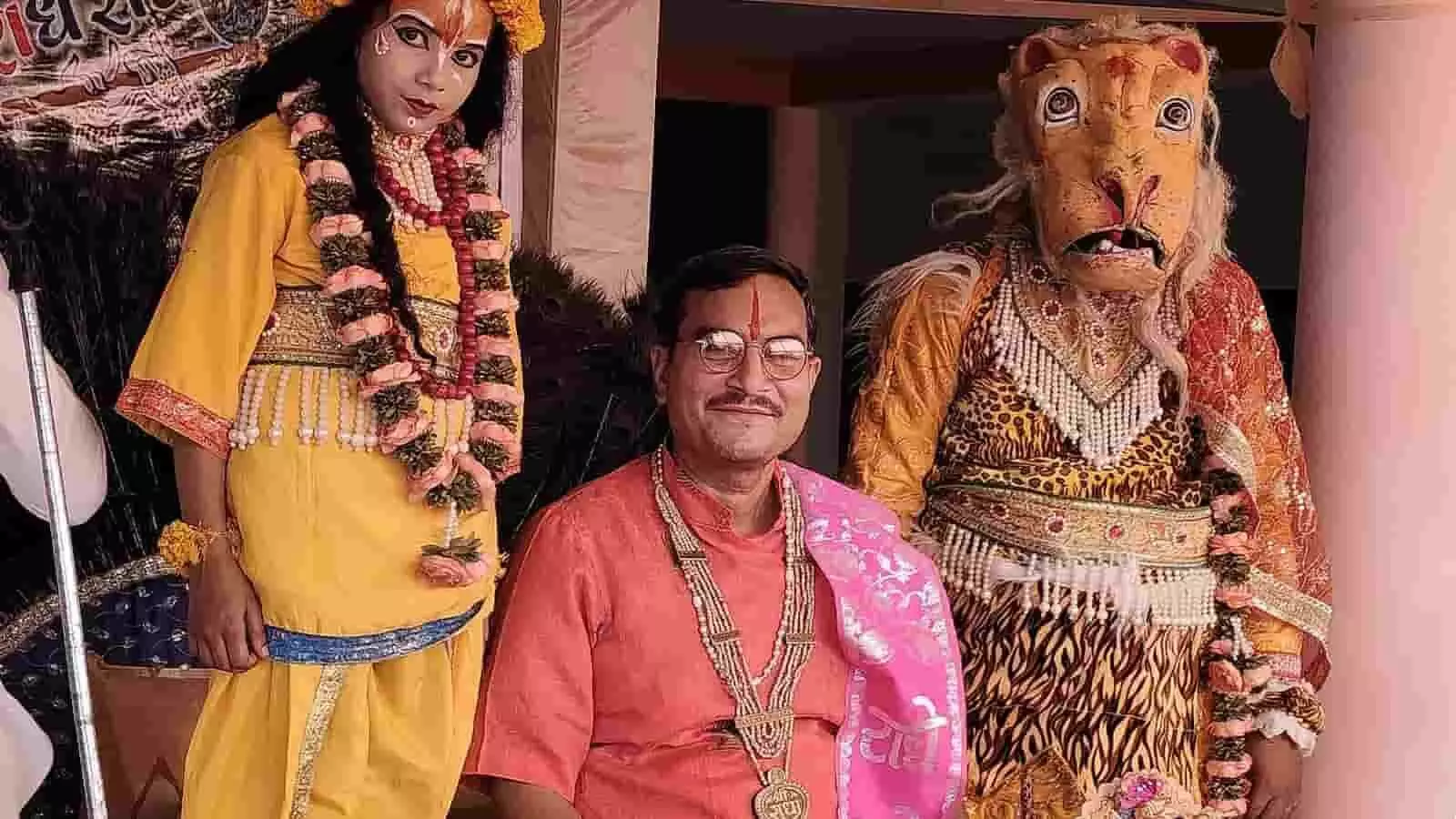 बौराज गांव में भागवत कथा के दौरान श्रीकृष्ण और नरसिंह की झांकी के साथ खड़े पंडित मुकुट बिहारी शास्त्री। बौराज गांव में भागवत कथा के दौरान श्रीकृष्ण और नरसिंह की झांकी के साथ खड़े पंडित मुकुट बिहारी शास्त्री।
