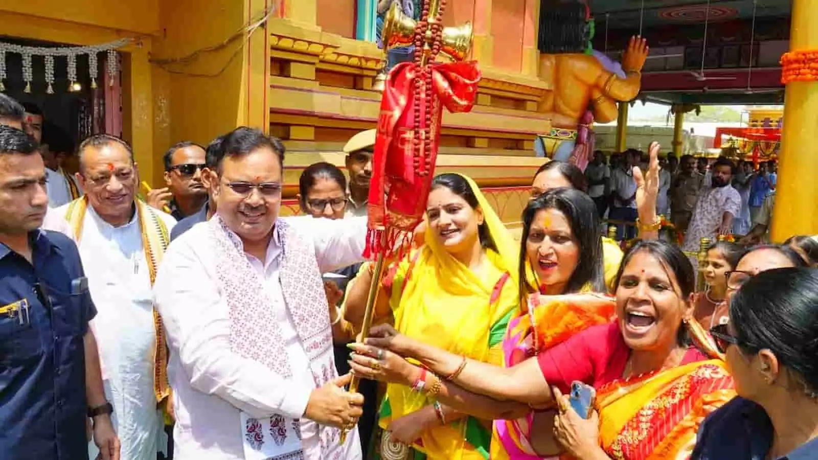 मंदिर परिसर में हाथ में ध्वज थामे पशुपालन मंत्री जोराराम कुमावत और अन्य श्रद्धालु उपस्थित हैं। मंदिर परिसर में हाथ में ध्वज थामे पशुपालन मंत्री जोराराम कुमावत और अन्य श्रद्धालु उपस्थित हैं।