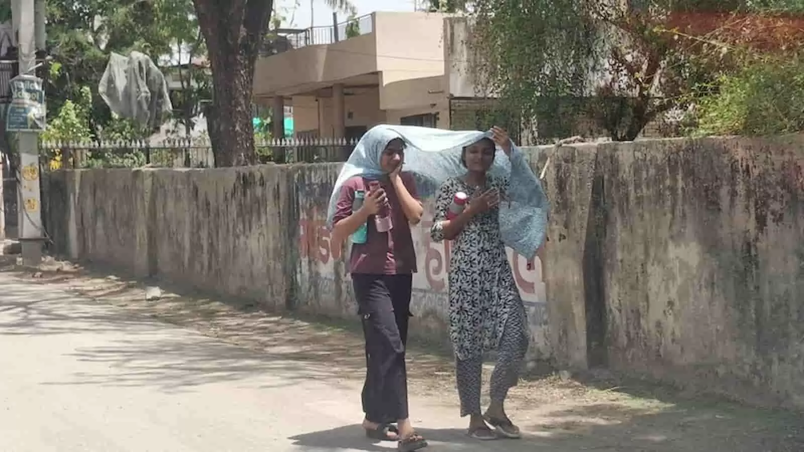 चित्तौड़गढ़ में भीषण गर्मी के दौरान धूप से बचने के लिए सिर पर कपड़ा ढककर सड़क पर चलती दो युवतियां। चित्तौड़गढ़ में भीषण गर्मी के दौरान धूप से बचने के लिए सिर पर कपड़ा ढककर सड़क पर चलती दो युवतियां।