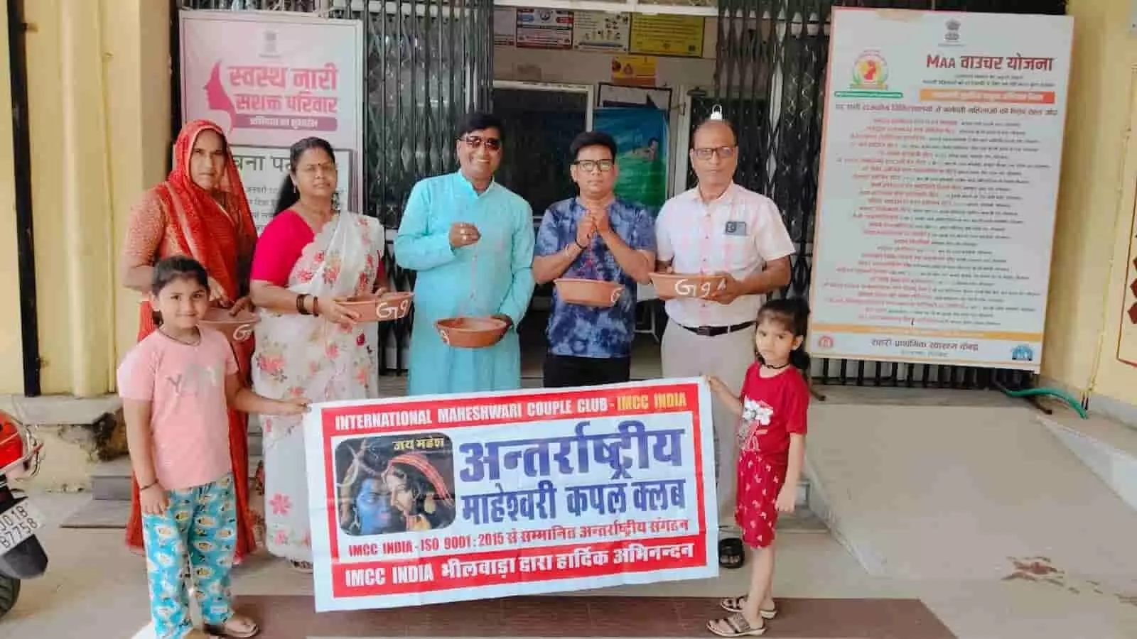 भीलवाड़ा के स्वास्थ्य केंद्र के बाहर बैनर के साथ खड़े लोग और पक्षियों के लिए रखे मिट्टी के परिंडे। भीलवाड़ा के स्वास्थ्य केंद्र के बाहर बैनर के साथ खड़े लोग और पक्षियों के लिए रखे मिट्टी के परिंडे।