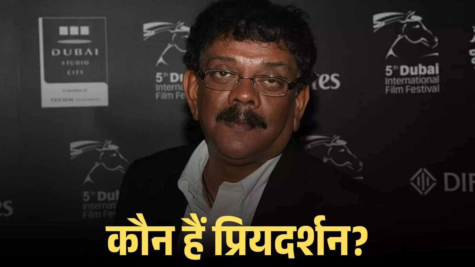 चश्मा पहने हुए निर्देशक प्रियदर्शन फिल्म फेस्टिवल के बैकड्रॉप के सामने खड़े हुए दिख रहे हैं। चश्मा पहने हुए निर्देशक प्रियदर्शन फिल्म फेस्टिवल के बैकड्रॉप के सामने खड़े हुए दिख रहे हैं।