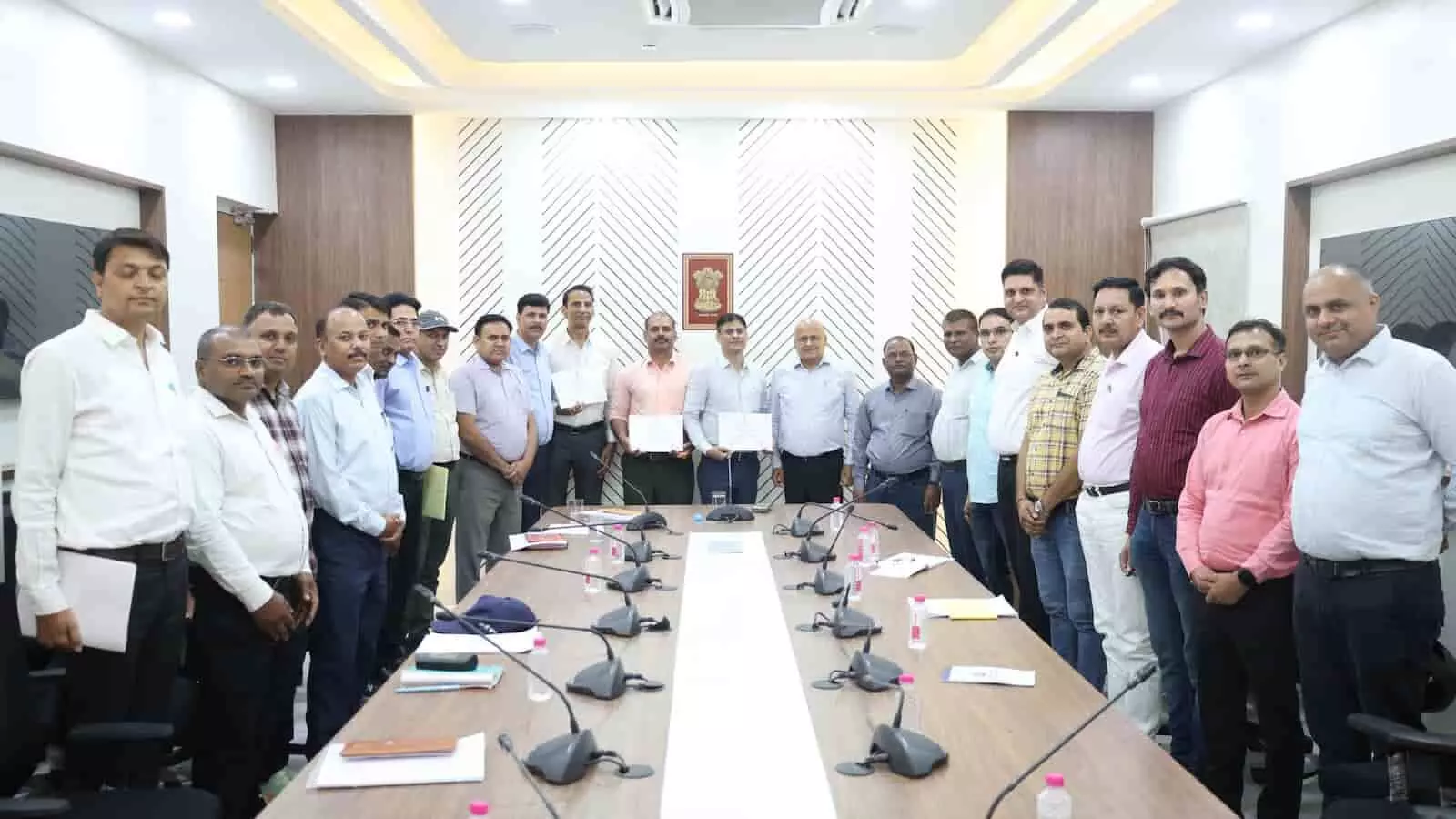 उत्तर पश्चिम रेलवे कार्यालय में मेज के चारों ओर खड़े अधिकारी न्यायिक समीक्षा बैठक में भाग लेते हुए।