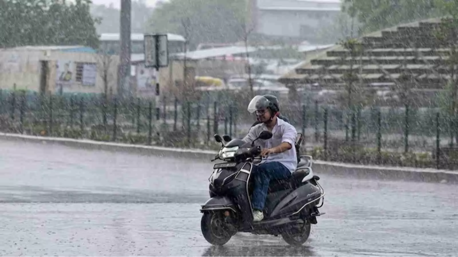 सड़क पर भारी बारिश के बीच स्कूटी चलाता हुआ एक व्यक्ति दक्षिण भारत में मानसून पूर्व वर्षा के दौरान। सड़क पर भारी बारिश के बीच स्कूटी चलाता हुआ एक व्यक्ति दक्षिण भारत में मानसून पूर्व वर्षा के दौरान।