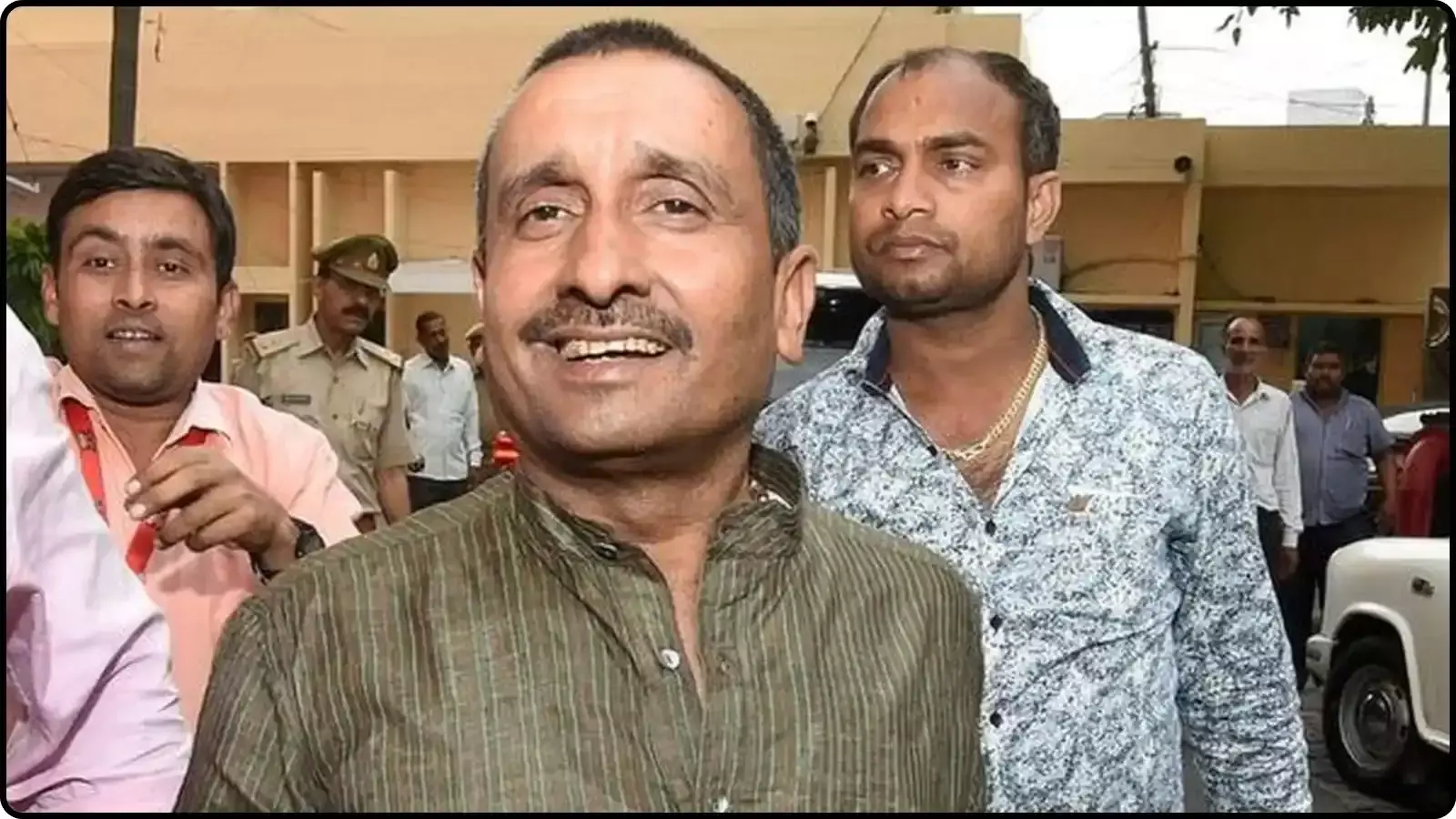 सफेद रंग की धारीदार कमीज पहने कुलदीप सिंह सेंगर पुलिस कर्मियों के साथ सार्वजनिक स्थान पर दिखाई दे रहे हैं।
