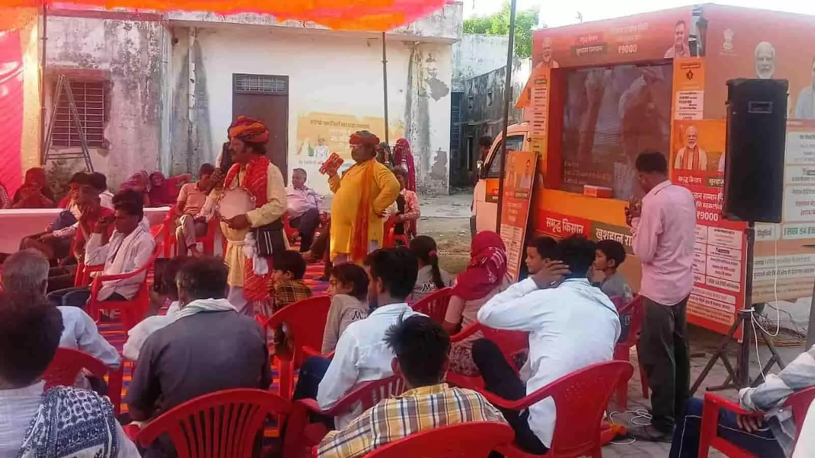 सवाई माधोपुर में ग्राम विकास रथ के पास लोक गीत गाते कला जत्थे के कलाकार और जानकारी सुनते ग्रामीण।
