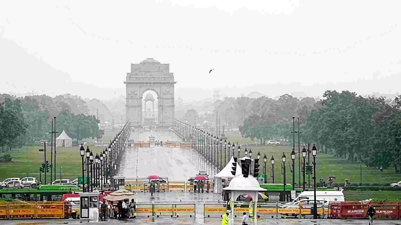 दिल्ली में इंडिया गेट के सामने बारिश और धुंध के बीच सड़क पर चलते लोग और बैरिकेडिंग। दिल्ली में इंडिया गेट के सामने बारिश और धुंध के बीच सड़क पर चलते लोग और बैरिकेडिंग।