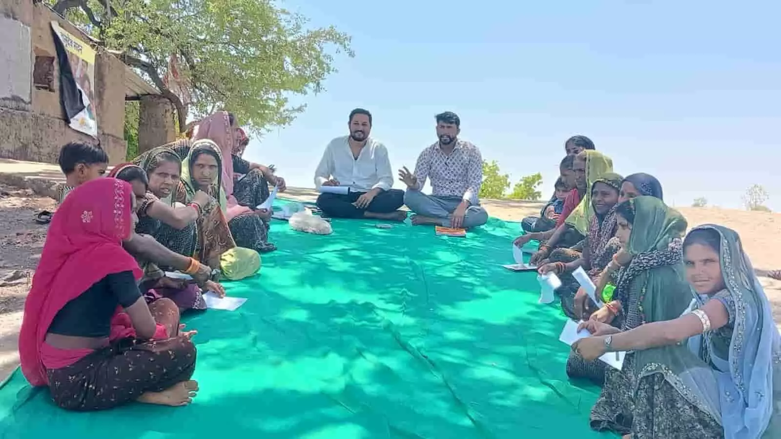 लसाडिया के स्कूल में हरी दरी पर बैठी माताएं और शैक्षणिक चर्चा करते फाउंडेशन प्रतिनिधि।
