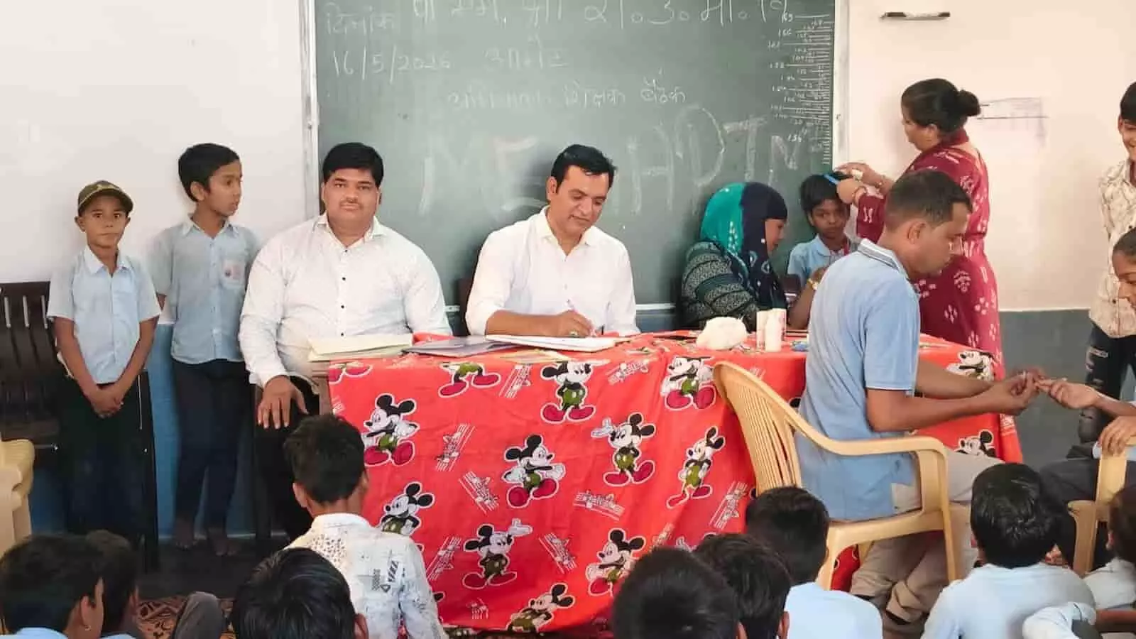 आमेट के पीएम श्री विद्यालय में मेगा पीटीएम के दौरान मेज पर बैठे शिक्षक और बच्चों का स्वास्थ्य परीक्षण करते स्वास्थ्यकर्मी। आमेट के पीएम श्री विद्यालय में मेगा पीटीएम के दौरान मेज पर बैठे शिक्षक और बच्चों का स्वास्थ्य परीक्षण करते स्वास्थ्यकर्मी।