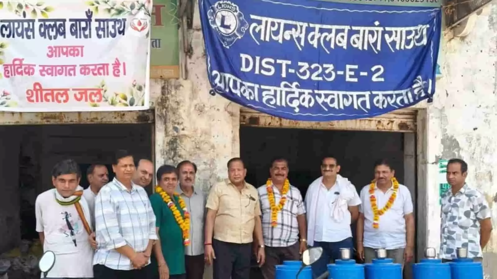 दीनदयाल पार्क के बाहर बैनर के नीचे खड़े लायंस क्लब के सदस्य और जल मंदिर के नीले कंटेनर। दीनदयाल पार्क के बाहर बैनर के नीचे खड़े लायंस क्लब के सदस्य और जल मंदिर के नीले कंटेनर।