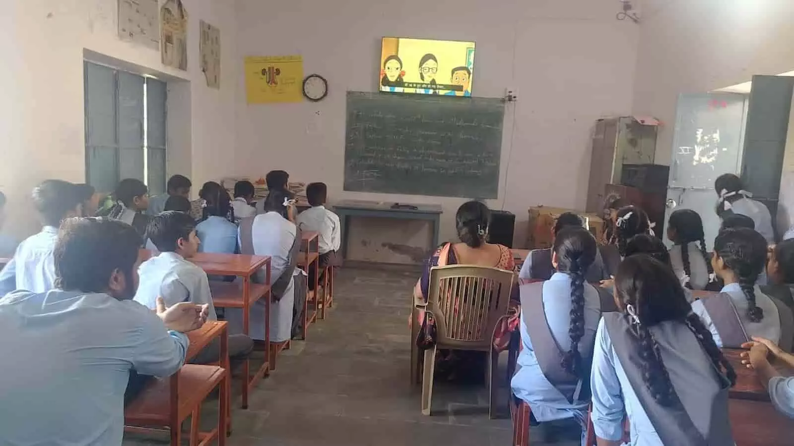 स्कूल के क्लासरूम में छात्र टीवी पर मतदान जागरूकता फिल्म देखते हुए। स्कूल के क्लासरूम में छात्र टीवी पर मतदान जागरूकता फिल्म देखते हुए।