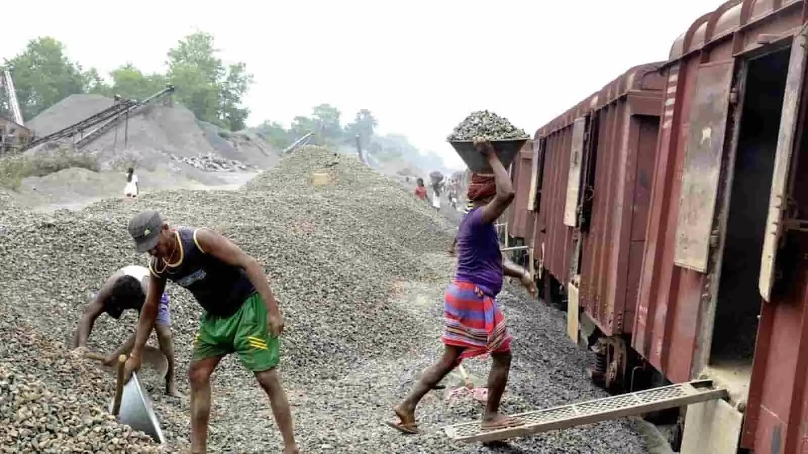 रेलवे स्टेशन पर मालगाड़ी के कवर्ड वैगन में स्टोन चिप्स लोड करते हुए मजदूर रेलवे स्टेशन पर मालगाड़ी के कवर्ड वैगन में स्टोन चिप्स लोड करते हुए मजदूर