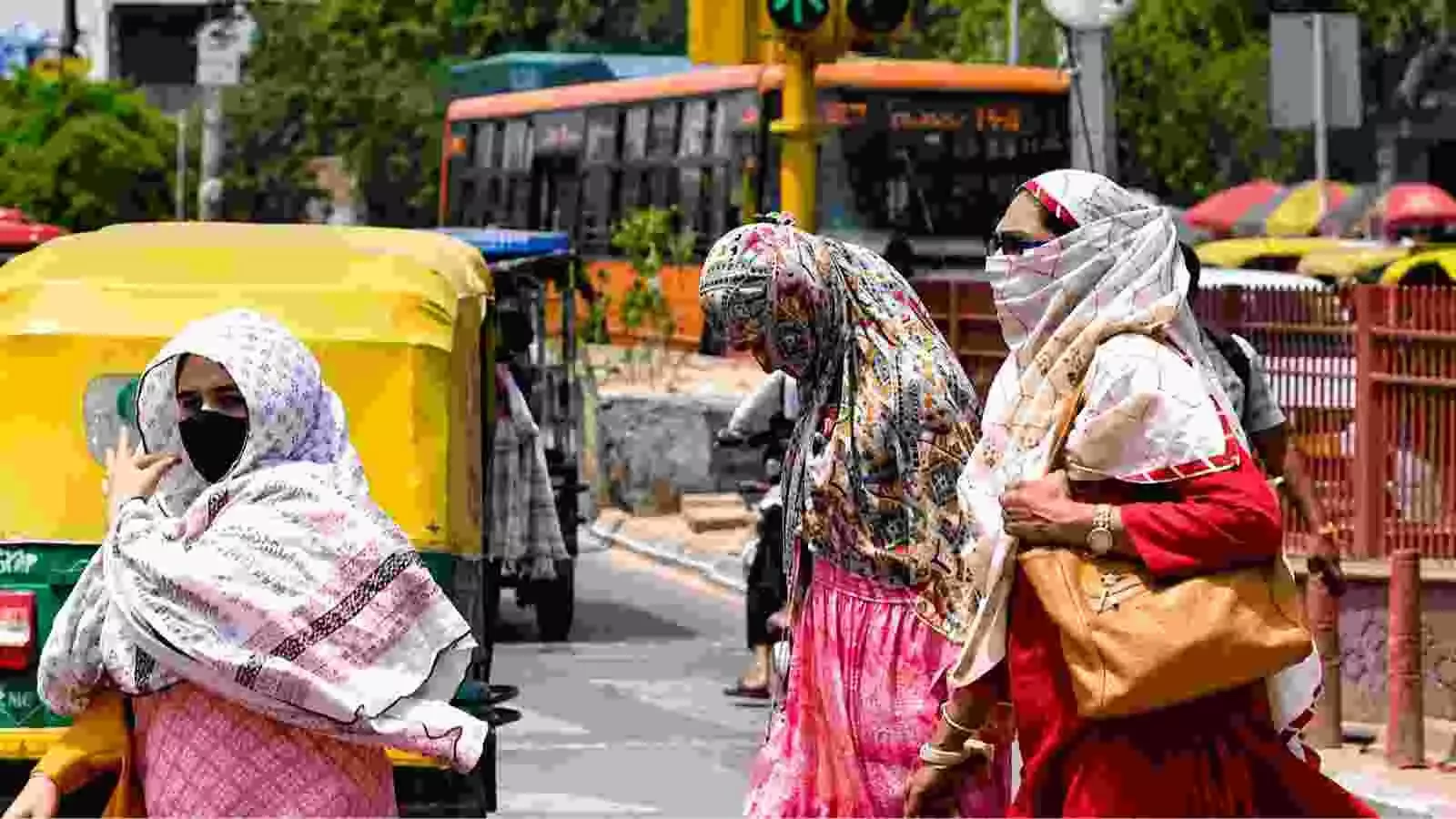 धूप से बचने के लिए चेहरे पर कपड़ा लपेटे हुए महिलाएं सड़क पार कर रही हैं। धूप से बचने के लिए चेहरे पर कपड़ा लपेटे हुए महिलाएं सड़क पार कर रही हैं।