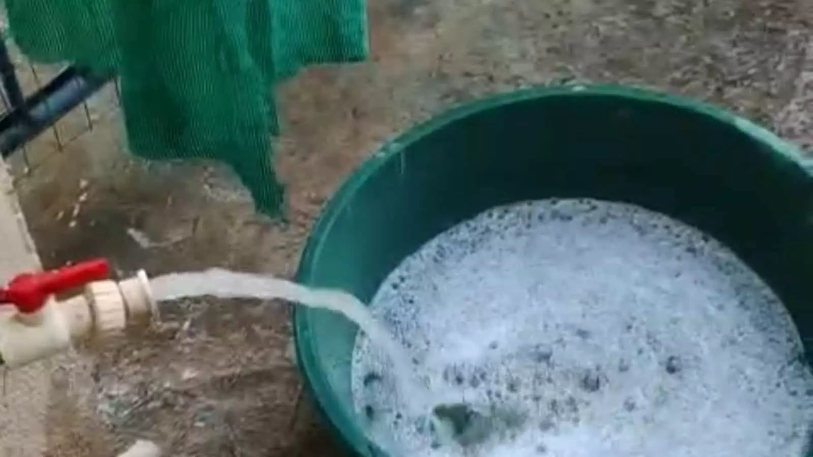 हरे रंग के टब में नल से आता हुआ सफेद झागदार और गंदा पानी। हरे रंग के टब में नल से आता हुआ सफेद झागदार और गंदा पानी।