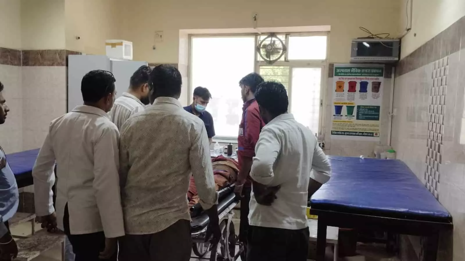 अस्पताल के स्ट्रेचर पर लेटा हुआ घायल व्यक्ति और उसके पास खड़े ग्रामीण तथा स्वास्थ्य कर्मी। अस्पताल के स्ट्रेचर पर लेटा हुआ घायल व्यक्ति और उसके पास खड़े ग्रामीण तथा स्वास्थ्य कर्मी।