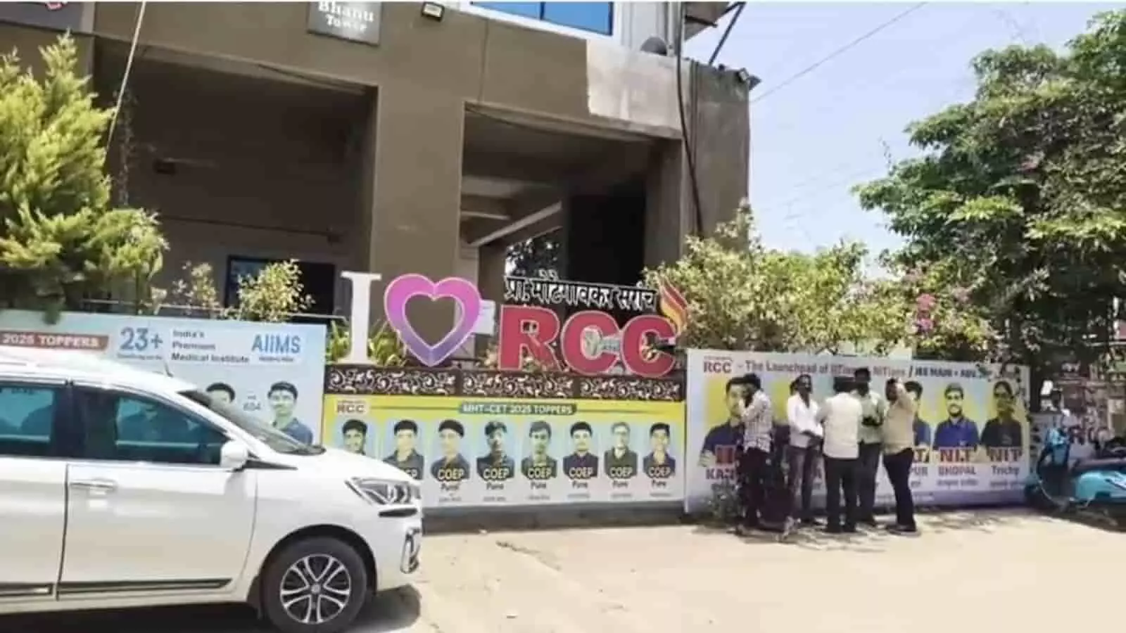लातूर में आरसीसी कोचिंग क्लासेस की इमारत के बाहर खड़े लोग और नीट टॉपर्स के पोस्टर। लातूर में आरसीसी कोचिंग क्लासेस की इमारत के बाहर खड़े लोग और नीट टॉपर्स के पोस्टर।