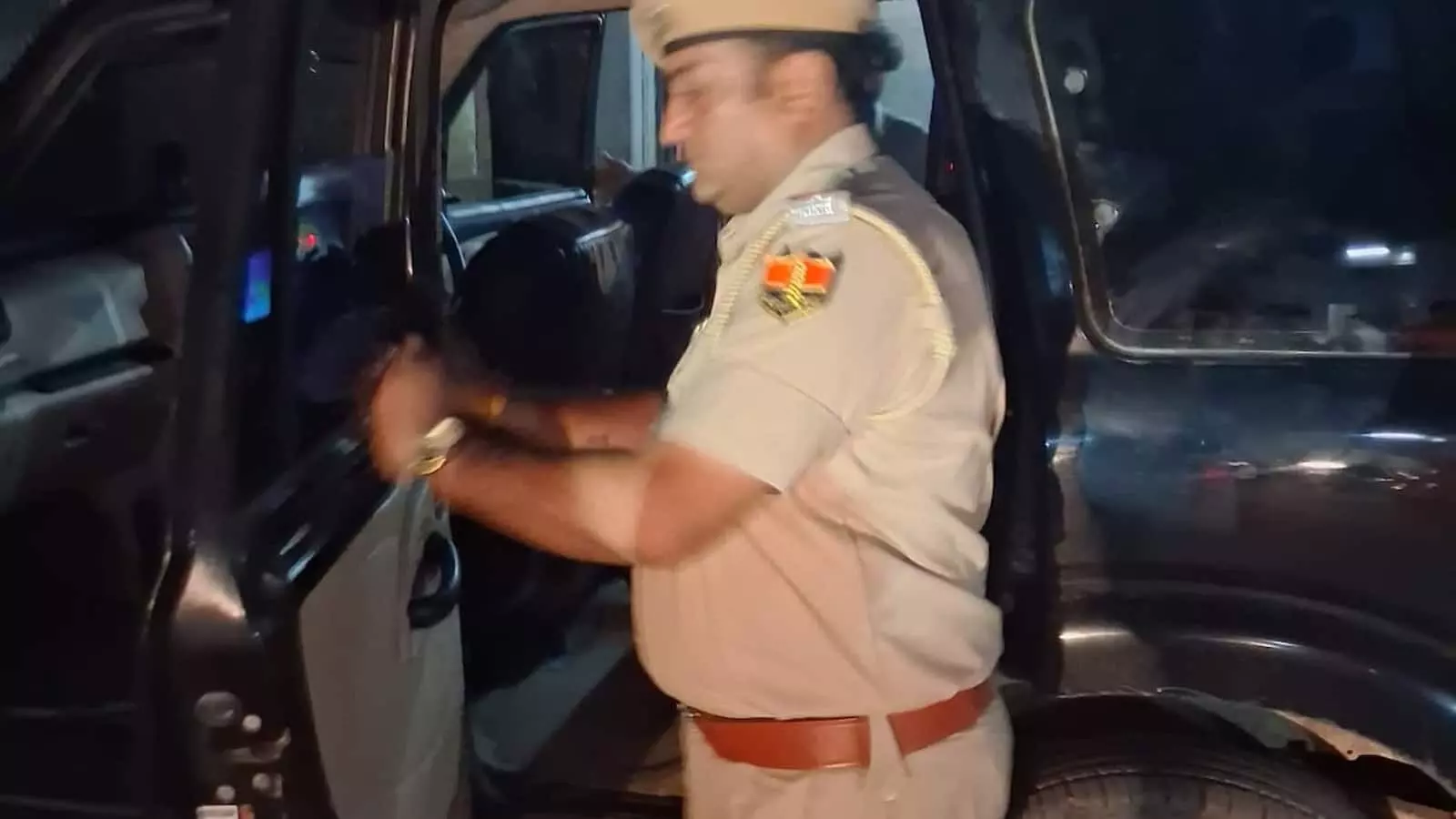 चित्तौड़गढ़ में सड़क पर खड़ी काली गाड़ी की जांच करते हुए खाकी वर्दी और टोपी पहने पुलिसकर्मी। चित्तौड़गढ़ में सड़क पर खड़ी काली गाड़ी की जांच करते हुए खाकी वर्दी और टोपी पहने पुलिसकर्मी।