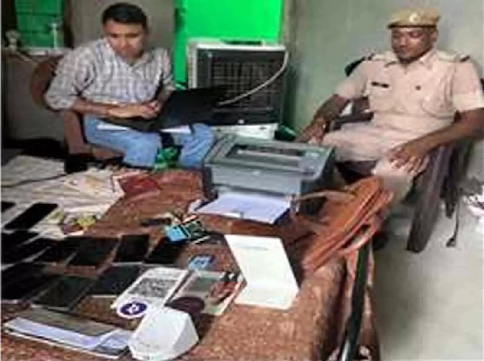 सवाई माधोपुर में खाट पर रखे 22 जब्तशुदा मोबाइल फोन के पास बैठा गिरफ्तार आरोपी बुद्धिप्रकाश मीणा। सवाई माधोपुर में खाट पर रखे 22 जब्तशुदा मोबाइल फोन के पास बैठा गिरफ्तार आरोपी बुद्धिप्रकाश मीणा।
