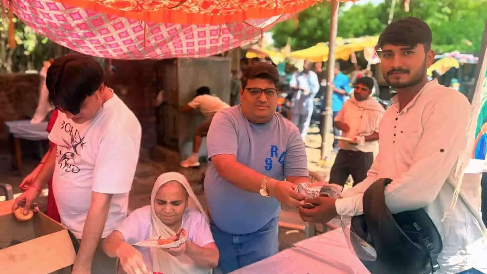 जयपुर के रामगढ़ मोड़ पर आयोजित सेवा शिविर में लोग स्टॉल से राहगीरों को भोजन वितरित कर रहे हैं।