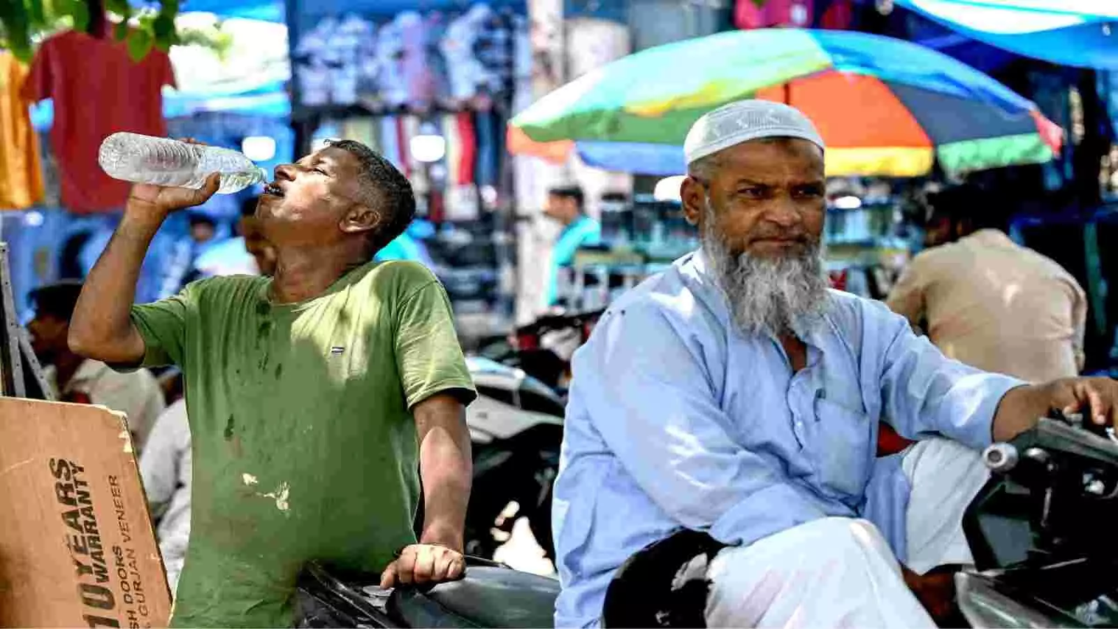 दिल्ली के बाजार में मोटरसाइकिल के पास बोतल से पानी पीता व्यक्ति। दिल्ली के बाजार में मोटरसाइकिल के पास बोतल से पानी पीता व्यक्ति।