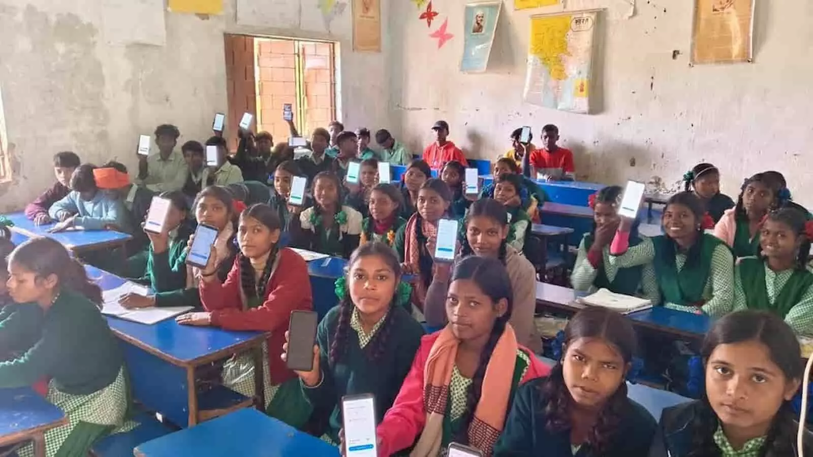 क्लासरूम में मोबाइल फोन स्क्रीन दिखाते स्कूली छात्र संपूर्ण शिक्षा कवच एआई लर्निंग प्रोग्राम के संदर्भ में