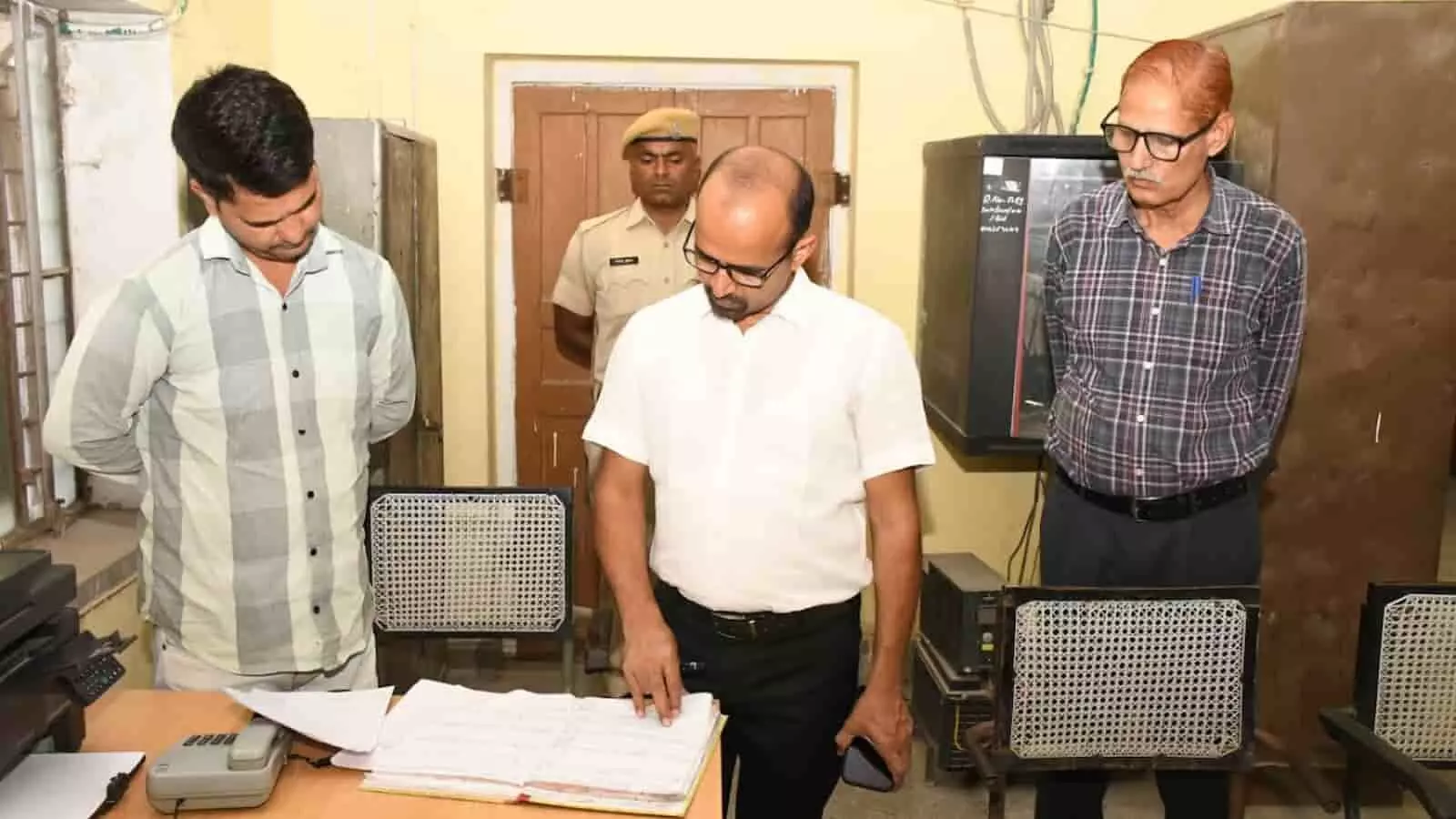मलारना डूंगर के सरकारी कार्यालय में पंजिका का निरीक्षण करते जिला कलक्टर काना राम और अधिकारीगण।