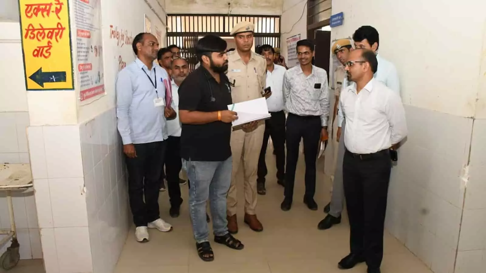 सरकारी कार्यालय परिसर में पुलिस और प्रशासनिक अधिकारियों के साथ निरीक्षण करते लोग।