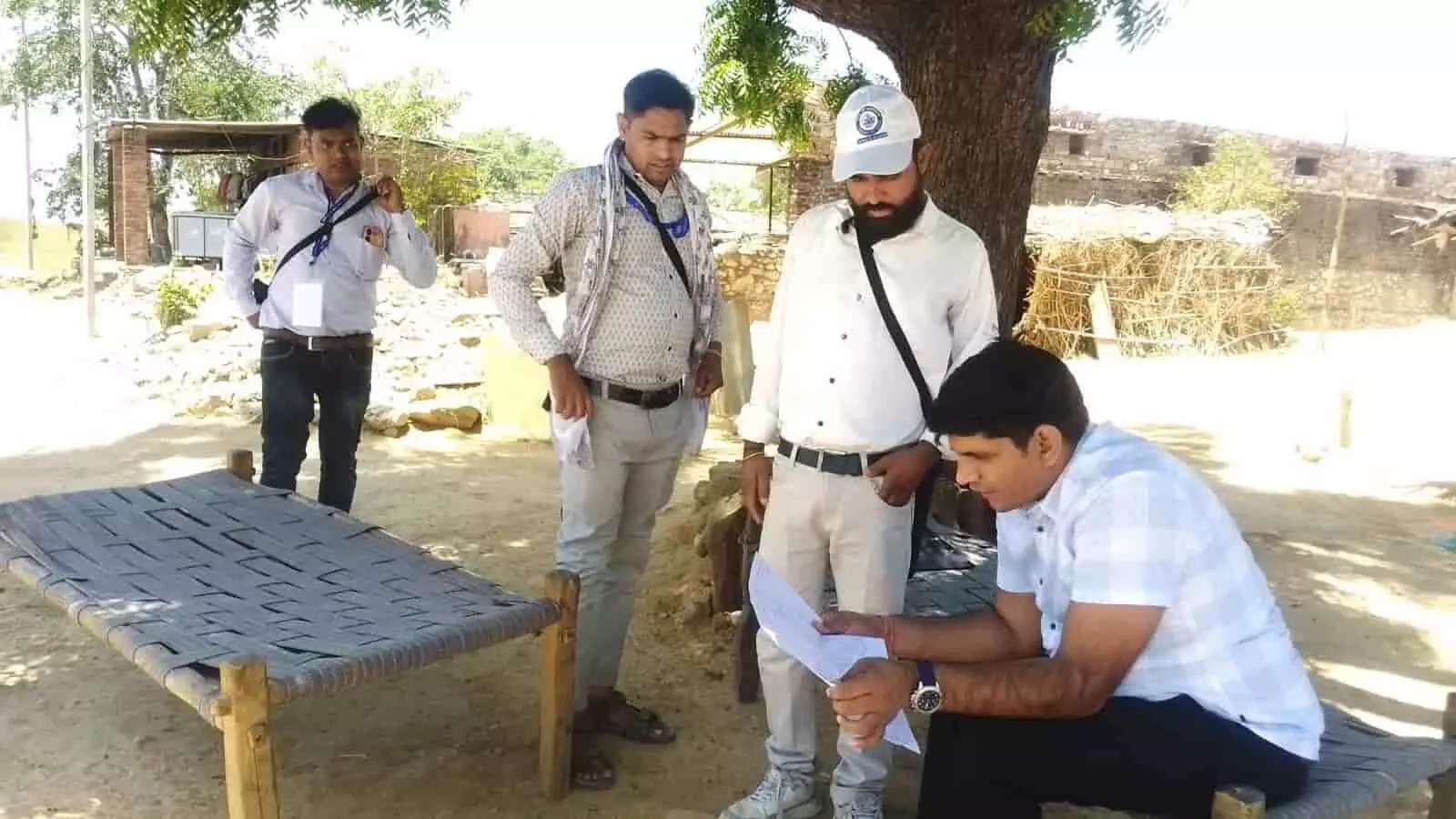 लसाड़िया में एक पेड़ की छांव के नीचे बैठकर प्रगणकों के साथ जनगणना दस्तावेज की जांच करते तहसीलदार रामजीलाल गुर्जर