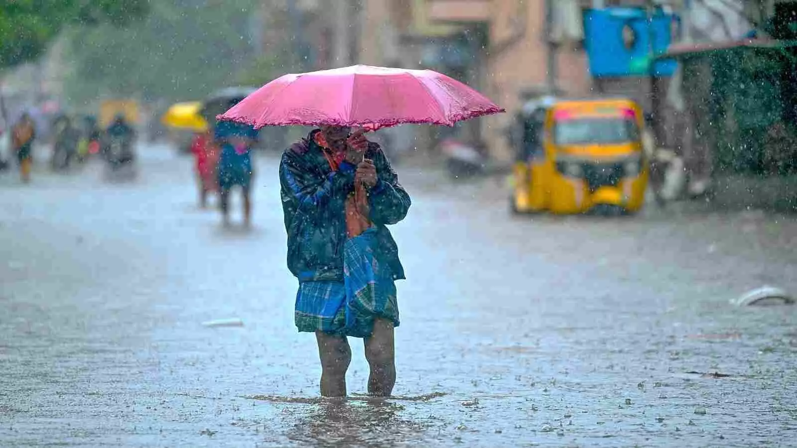 भारी बारिश में गुलाबी छाता लेकर जलभराव वाली सड़क पर चलता व्यक्ति केरल में प्री-मानसून के संदर्भ में| भारी बारिश में गुलाबी छाता लेकर जलभराव वाली सड़क पर चलता व्यक्ति केरल में प्री-मानसून के संदर्भ में|
