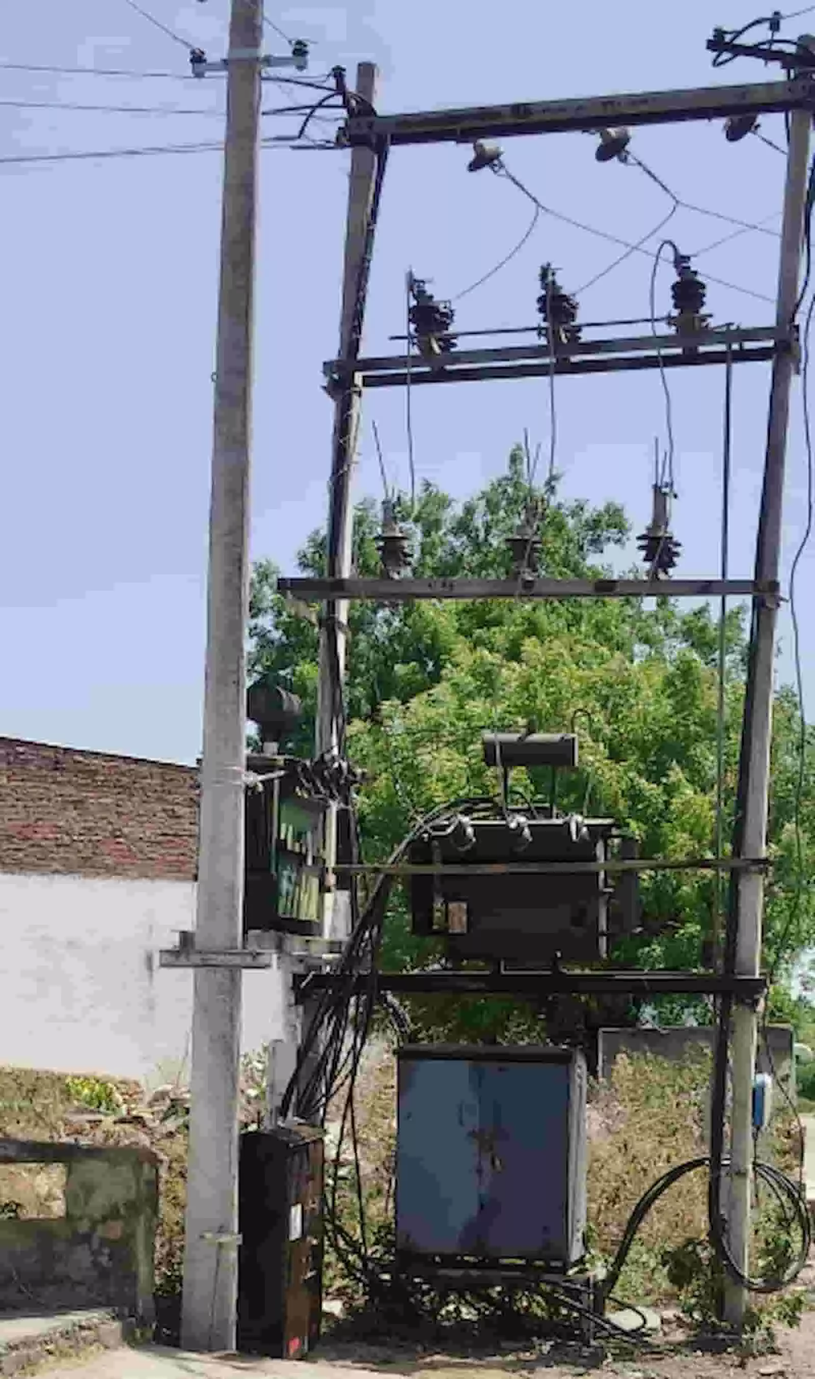 बिजली के दो खंभों के बीच हवा में लोहे के फ्रेम पर टिका हुआ एक नया विद्युत ट्रांसफार्मर।