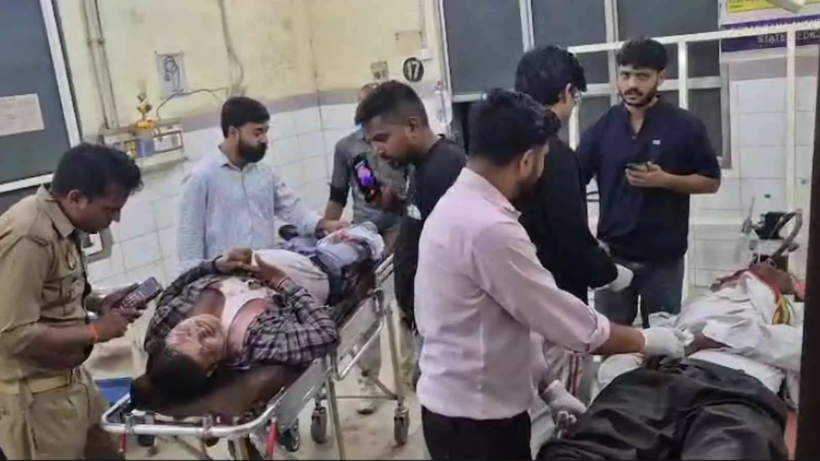 एटा के अस्पताल में स्ट्रेचर पर लेटे घायल मरीज और इलाज करते स्वास्थ्य कर्मी