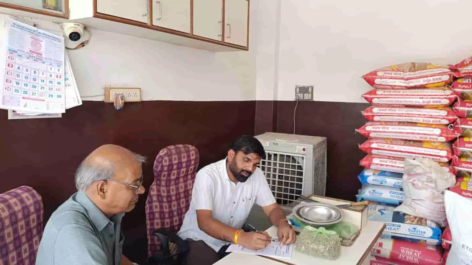 कृषि केंद्र में दुकान पर बैठे अधिकारी द्वारा दस्तावेज और स्टॉक पंजिका का भौतिक सत्यापन किया जाना।