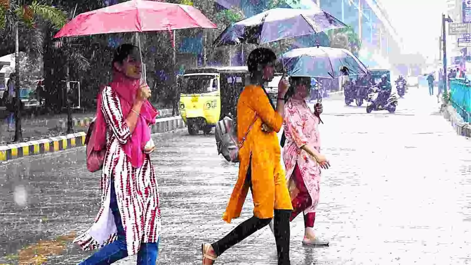 तेज बारिश के दौरान हाथ में छतरी लिए सड़क पर चलती हुई तीन महिलाएं। तेज बारिश के दौरान हाथ में छतरी लिए सड़क पर चलती हुई तीन महिलाएं।