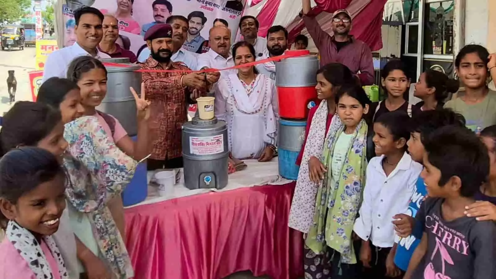 नयागांव स्कूल कोटा के बाहर फीता काटकर शीतल जल प्याऊ का उद्घाटन करते अतिथि और खड़े बच्चे नयागांव स्कूल कोटा के बाहर फीता काटकर शीतल जल प्याऊ का उद्घाटन करते अतिथि और खड़े बच्चे