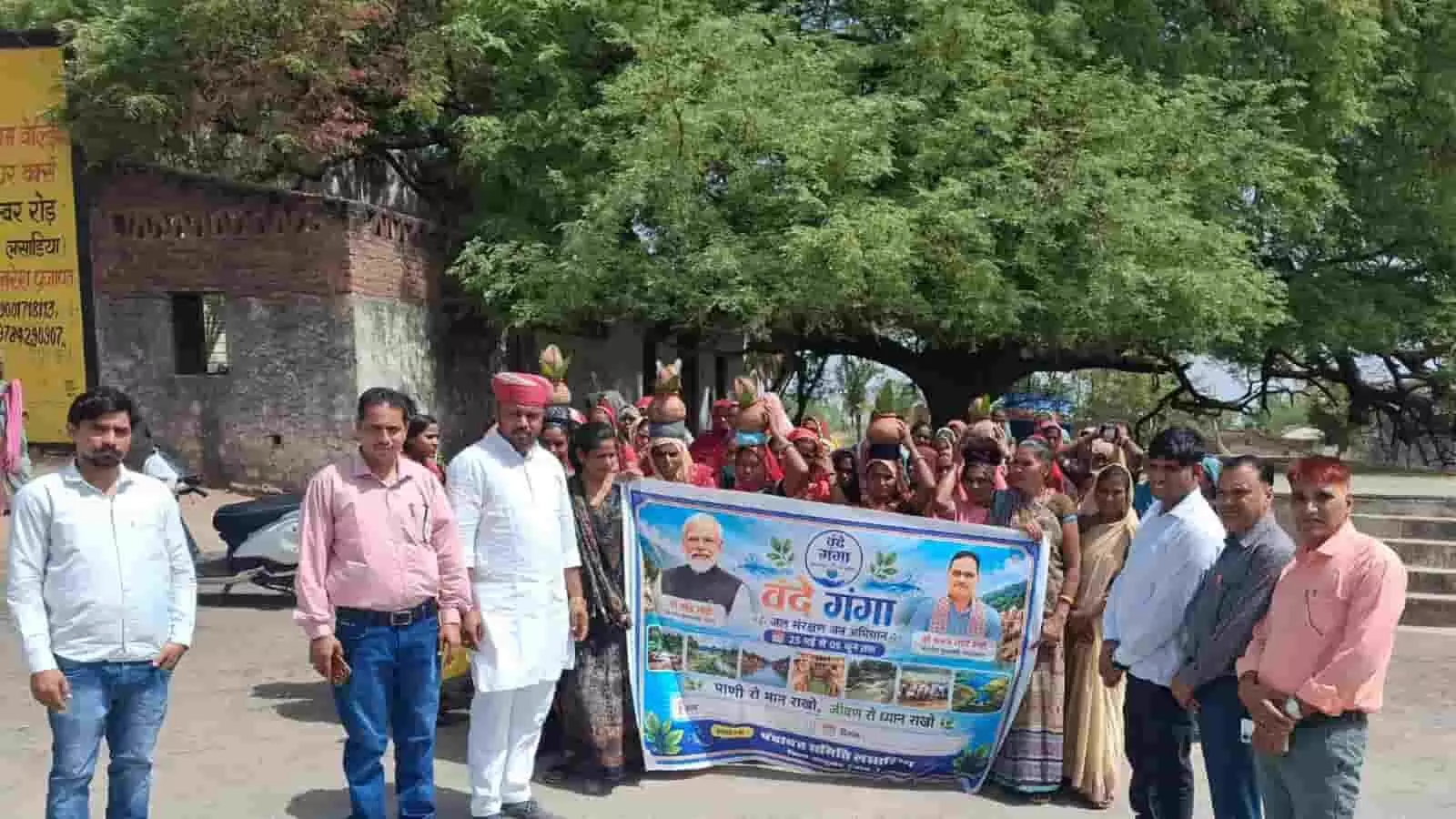 लसाडिया में जल संरक्षण अभियान के शुभारंभ पर बैनर थामे खड़े जनप्रतिनिधि, अधिकारी और कलश लिए महिलाएं।