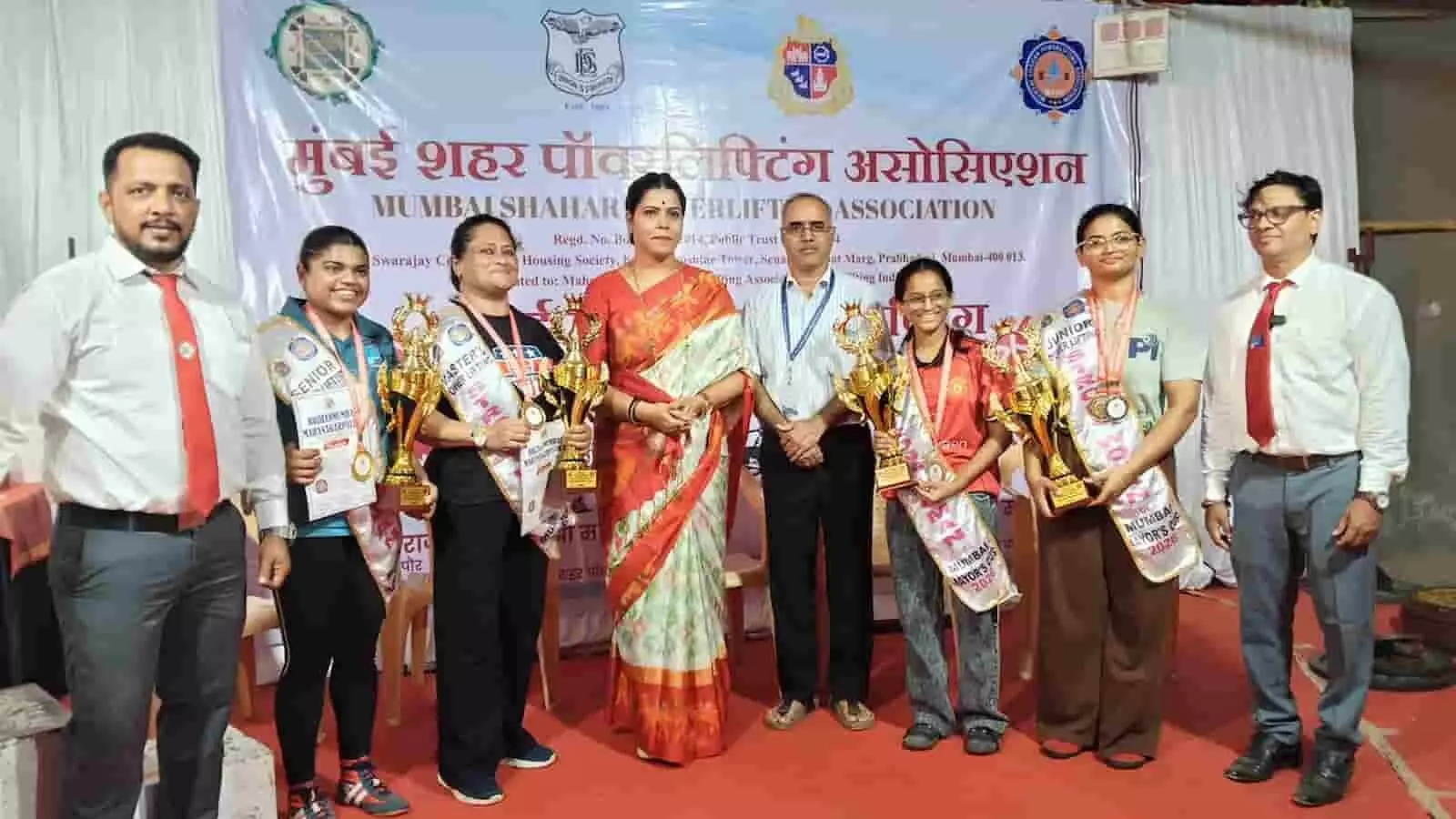 मुंबई में आयोजित मेयर कप पावरलिफ्टिंग स्पर्धा के मंच पर ट्रॉफी और मेडल के साथ खड़े विजेता खिलाड़ी और मेयर रितू तावडे। मुंबई में आयोजित मेयर कप पावरलिफ्टिंग स्पर्धा के मंच पर ट्रॉफी और मेडल के साथ खड़े विजेता खिलाड़ी और मेयर रितू तावडे।