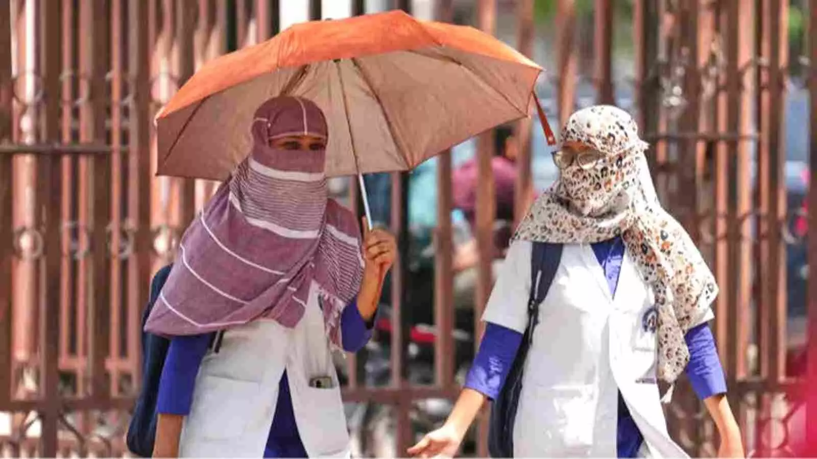 चिलचिलाती धूप में धूप का चश्मा और स्कार्फ पहनकर छतरी के सहारे सड़क पर पैदल चलती महिलाएं। चिलचिलाती धूप में धूप का चश्मा और स्कार्फ पहनकर छतरी के सहारे सड़क पर पैदल चलती महिलाएं।