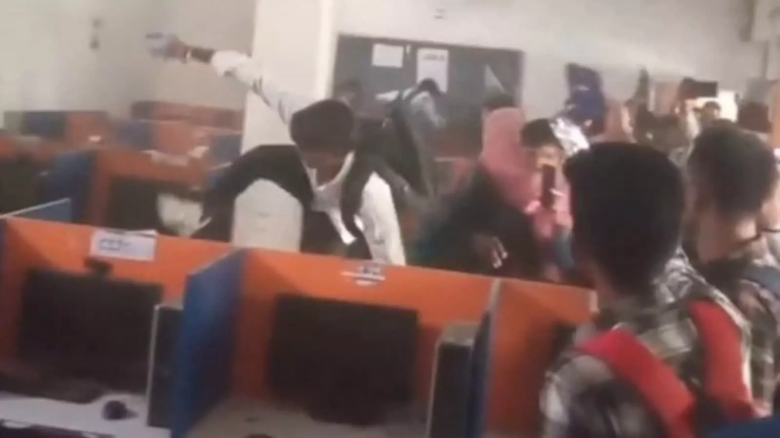 परीक्षा केंद्र के कंप्यूटर लैब में टेबल पर चढ़कर तोड़फोड़ करते हुए छात्र और विरोध प्रदर्शन करते अभ्यर्थी। परीक्षा केंद्र के कंप्यूटर लैब में टेबल पर चढ़कर तोड़फोड़ करते हुए छात्र और विरोध प्रदर्शन करते अभ्यर्थी।