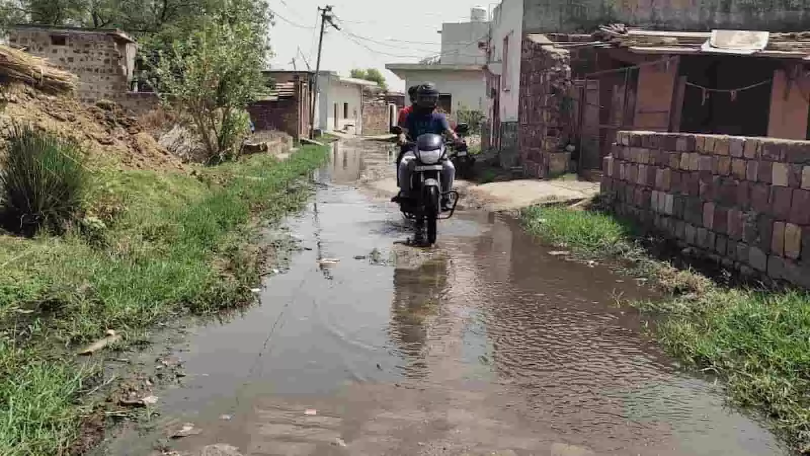 बयाना के ब्रह्मबाद गांव की जलमग्न सड़क पर मोटरसाइकिल से जाते दो लोग