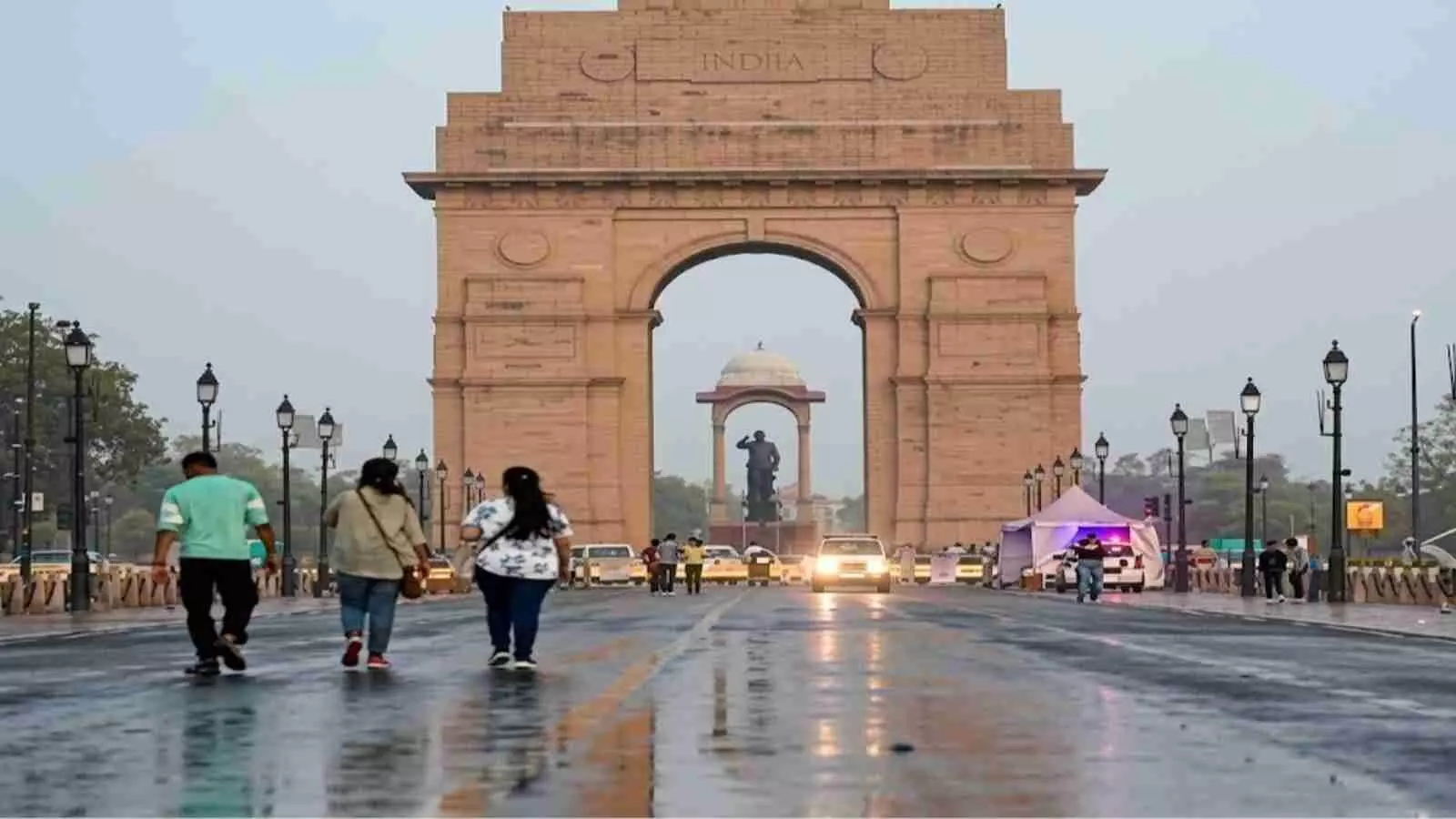 इंडिया गेट के सामने सड़क पर हल्की बारिश के बाद कुछ लोग टहलते हुए दिख रहे हैं। इंडिया गेट के सामने सड़क पर हल्की बारिश के बाद कुछ लोग टहलते हुए दिख रहे हैं।