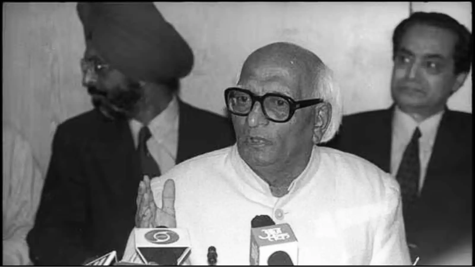 माइक के सामने बैठकर बोलते हुए चश्मा पहने पूर्व केंद्रीय मंत्री प्रो. मधु दंडवते एक प्रेस वार्ता के संदर्भ में दिख रहे हैं। माइक के सामने बैठकर बोलते हुए चश्मा पहने पूर्व केंद्रीय मंत्री प्रो. मधु दंडवते एक प्रेस वार्ता के संदर्भ में दिख रहे हैं।