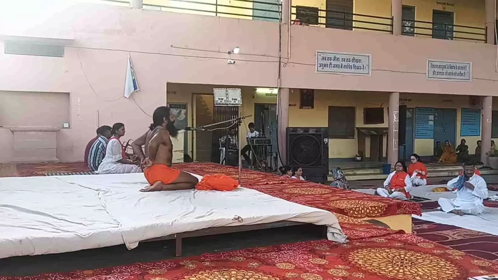 छोटीसादड़ी के स्कूल परिसर में दरी पर बैठकर योगाभ्यास करते हुए पुरुष योग साधक।